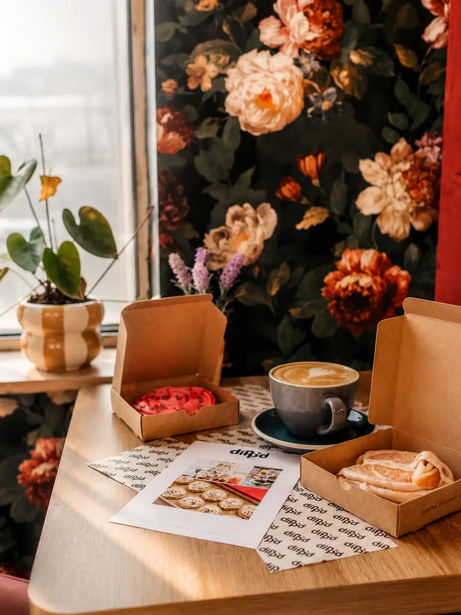A cosy cafe table with coffee, pastries and plants inside Cafe in the Park